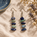 Earrings on linen beside a blue ceramic dish