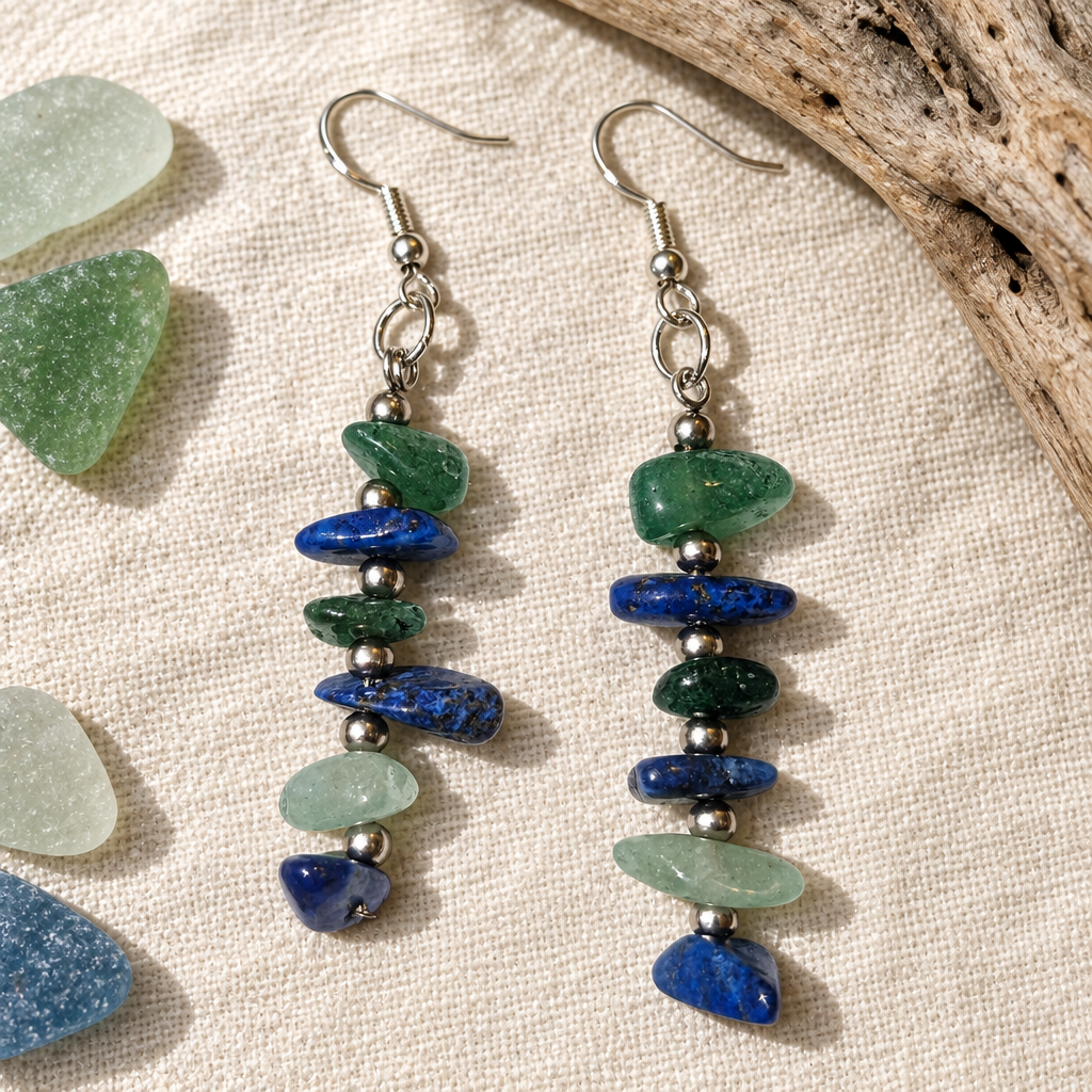 Earrings on linen beside sea glass